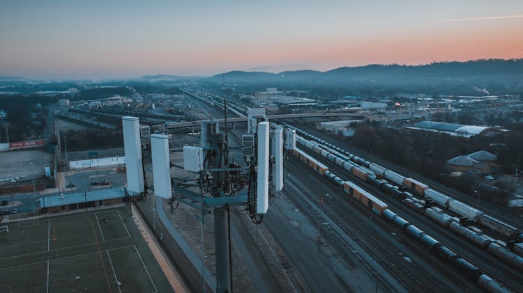 Cell Tower In City Suburban Area With Railroad Station At Sundown