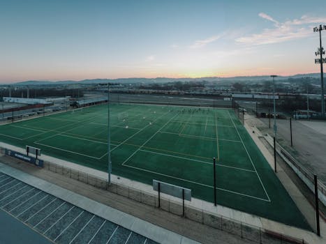 Drone view of a soccer field in Chattanooga, TN during sunset, with people practicing under vibrant skies.