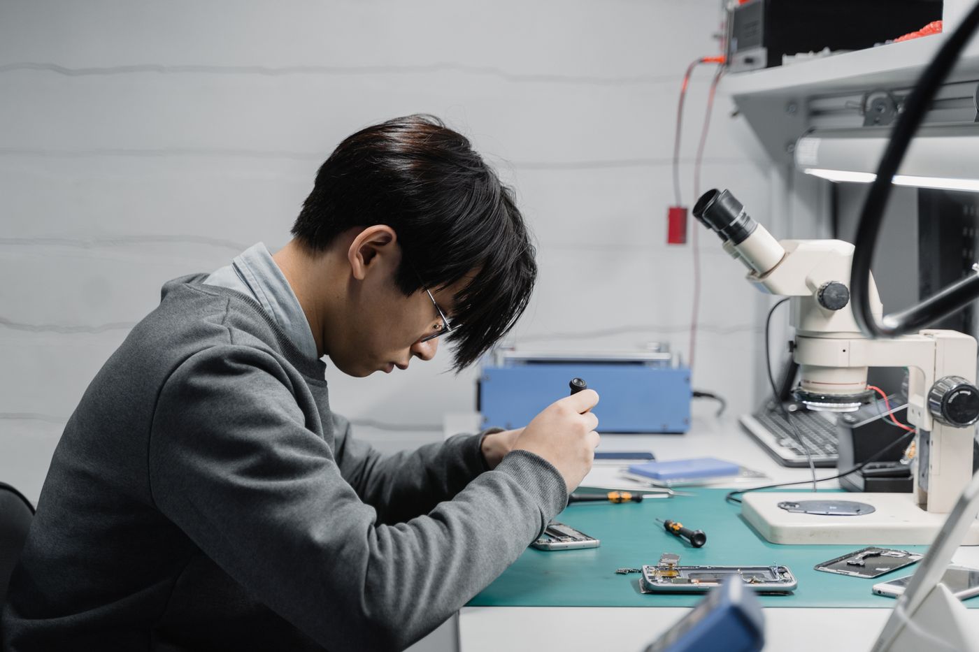 Real technician repairing a mobile device under a microscope