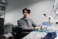 A man in Gray Jacket Repairing a Device