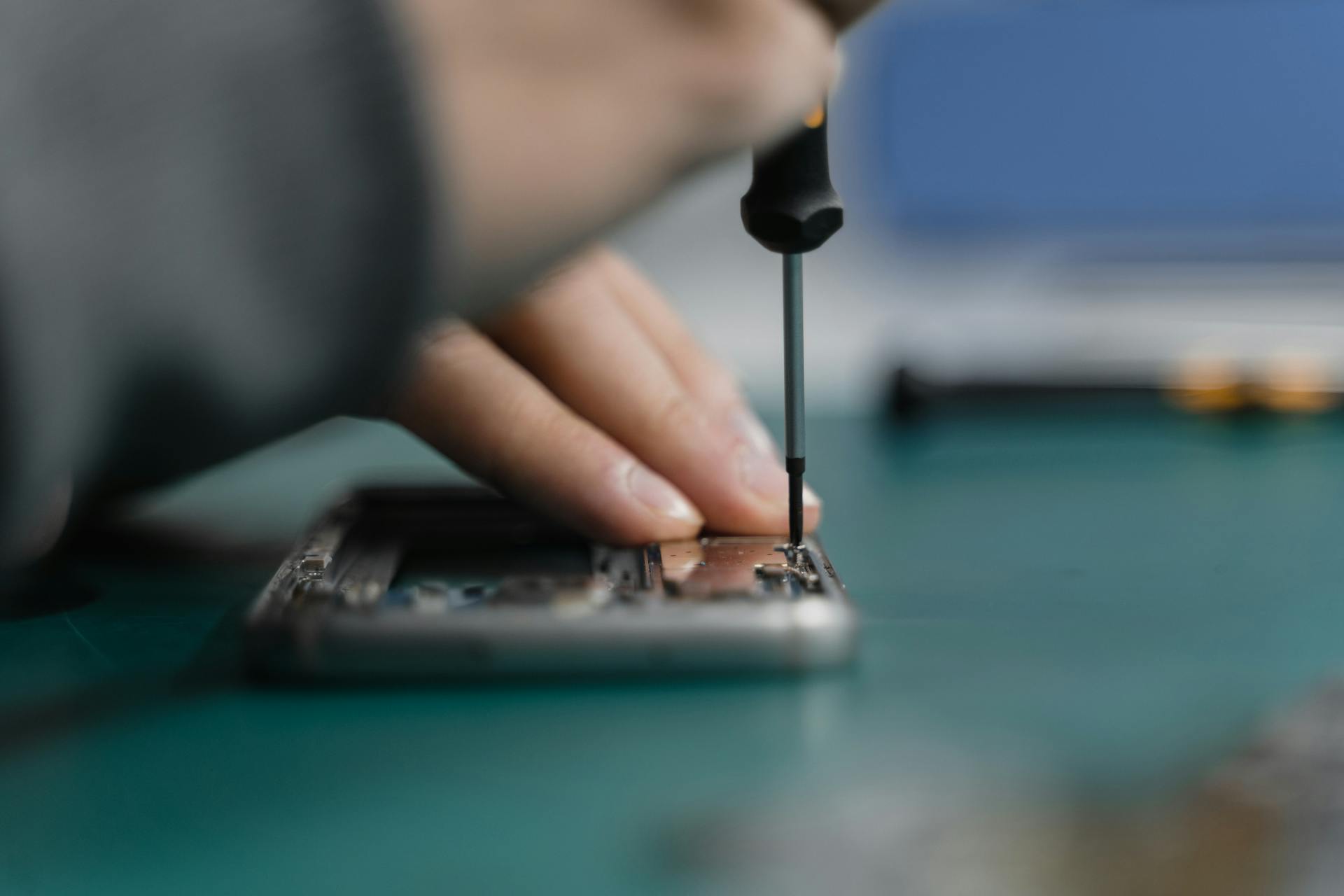 Detailed shot of smartphone repair with a screwdriver and hand close-up.