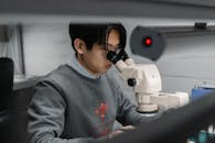Man in Gray Sweater Using Black and Silver Camera