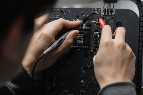 Person Using a Soldering Iron on a Circuit Board