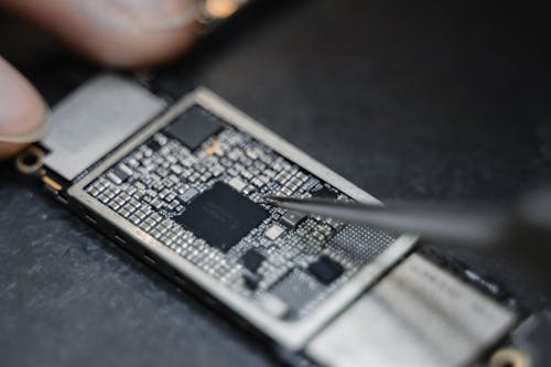 Person Using Tweezers on a Circuit Board