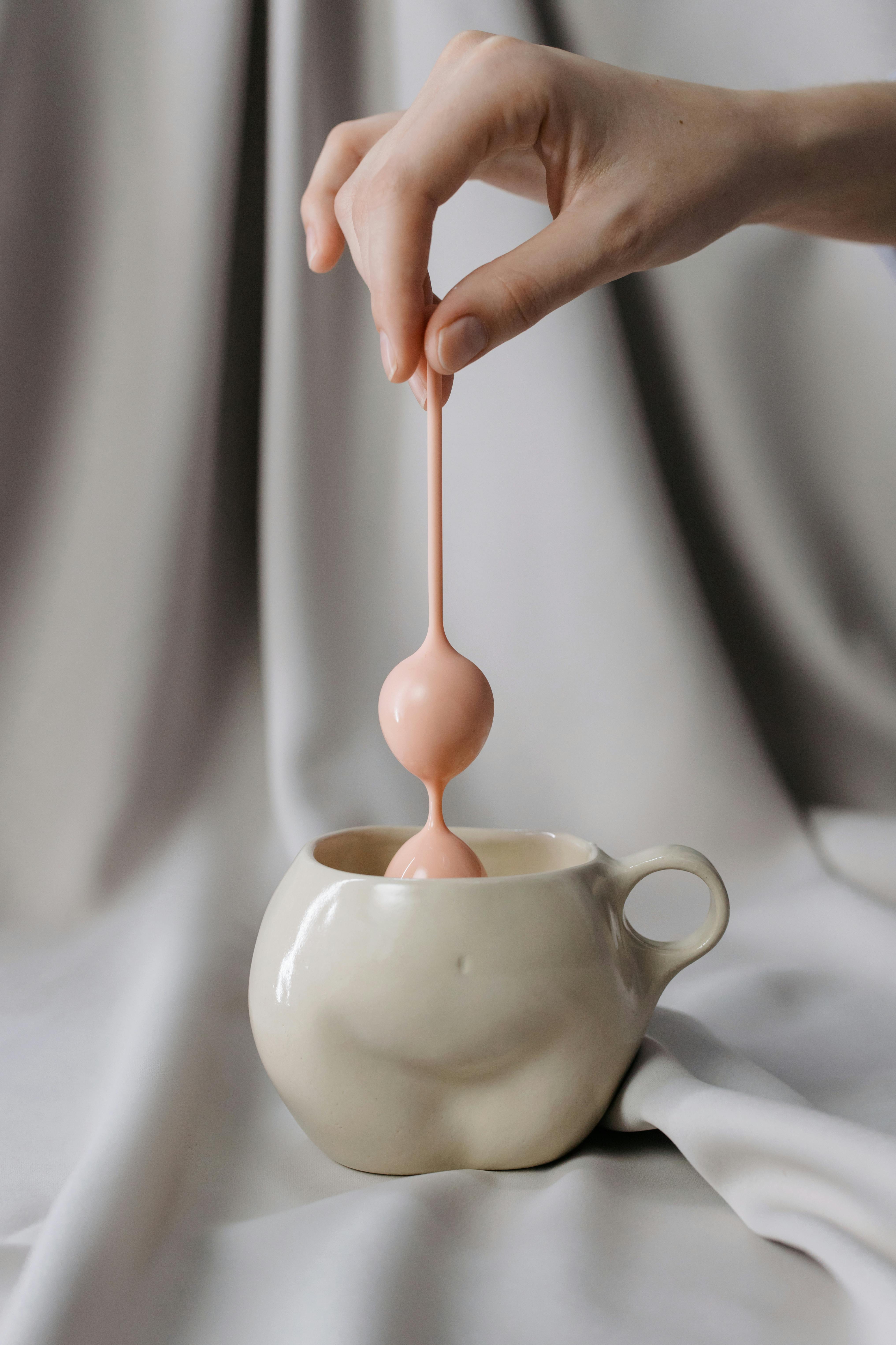 woman hand holding anal bead stick into mug