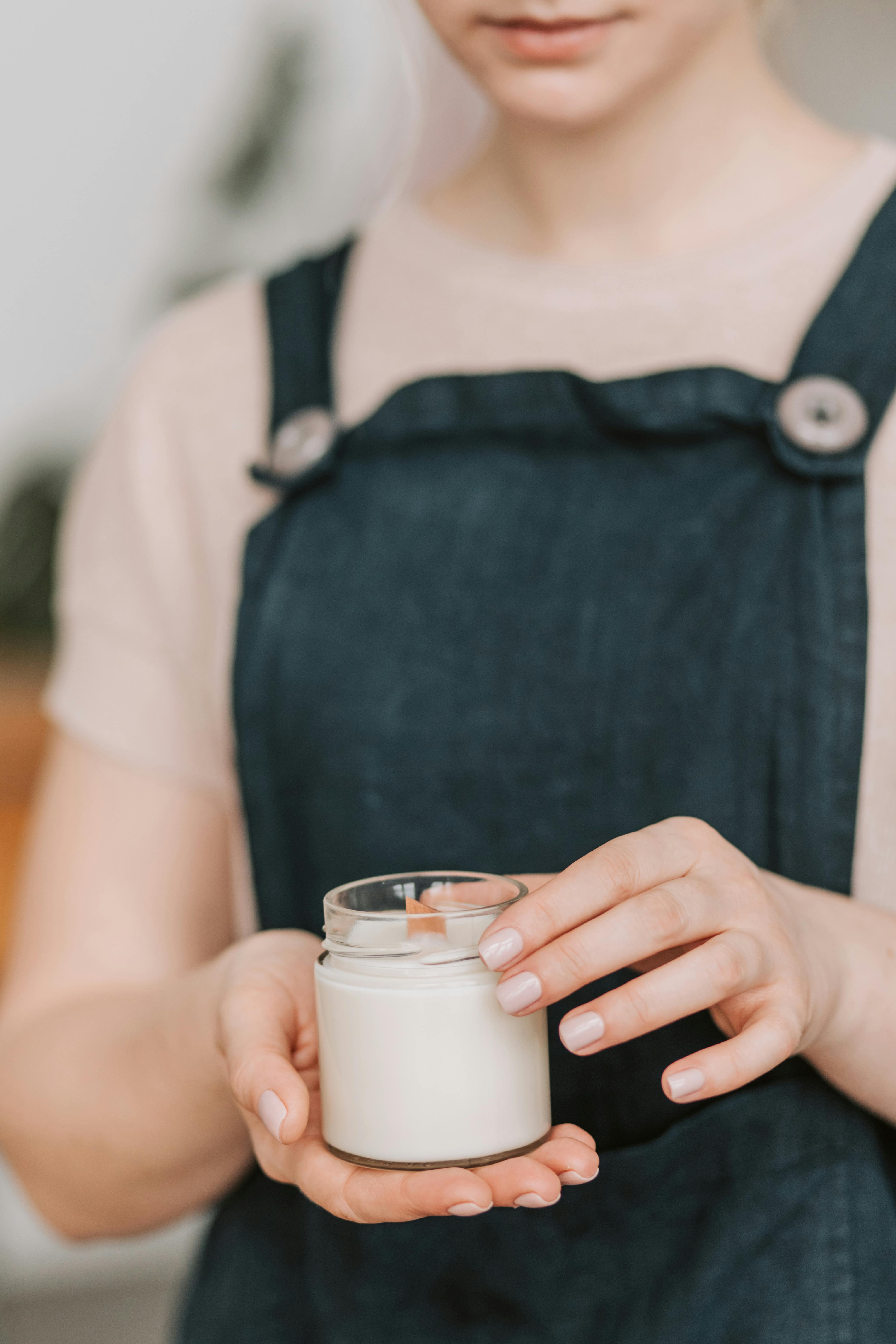 close up of woman in an apron holding a handmade candle