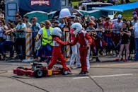 两名穿着卡丁车服的赛车手在赛道上握手，身后是欢呼的观众