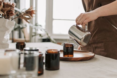 Free Close-up of a woman pouring wax into jars for handmade candle making. Stock Photo