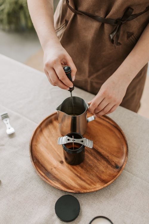 Free Close-up of a person making candles with metal cup and tools on a wooden tray. Stock Photo