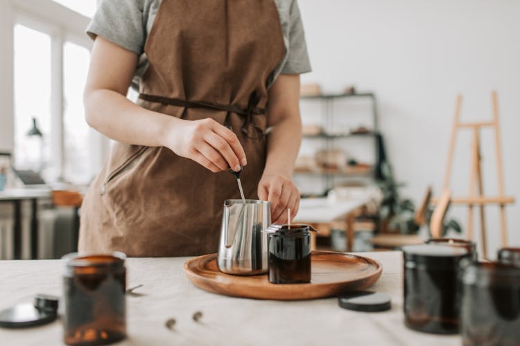 Person Wearing An Apron Holding A Stainless Pitcher