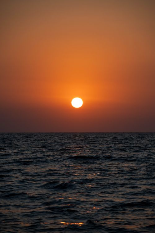 Free Breathtaking ocean sunset with vibrant orange hues and a tranquil sea view. Stock Photo