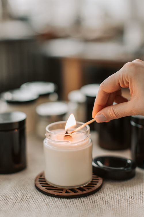 Free Close-up of a hand lighting a handmade candle with a matchstick, creating a cozy ambiance. Stock Photo