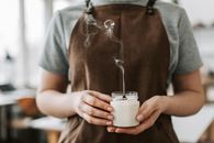 Person in Brown Apron Holding Unlighted Candle