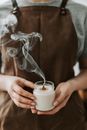 Person in Brown Apron Holding White Unlighted Candle