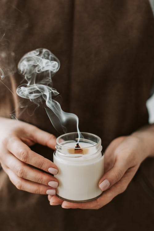 Person Holding Smoking Candles in Jar