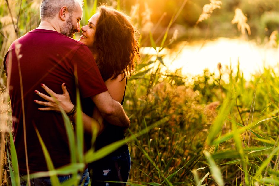 Una pareja abrazándose en un prado iluminado por el sol, capturando amor e intimidad en la naturaleza.
