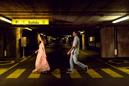 A couple strolling in a dimly lit underground parking garage in Toledo, Spain.