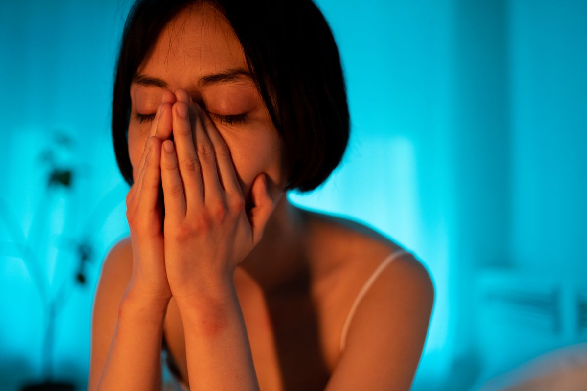 Woman lying awake at night with intrusive thoughts after infidelity, seeking calm