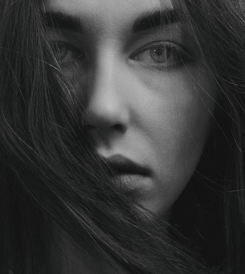 Free Close-up monochrome portrait capturing a woman's intense gaze and flowing hair. Stock Photo