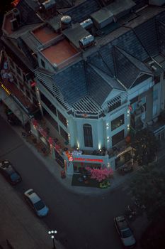 Aerial view showcasing a bustling urban corner with a coffee shop, vehicles, and vibrant night lights.
