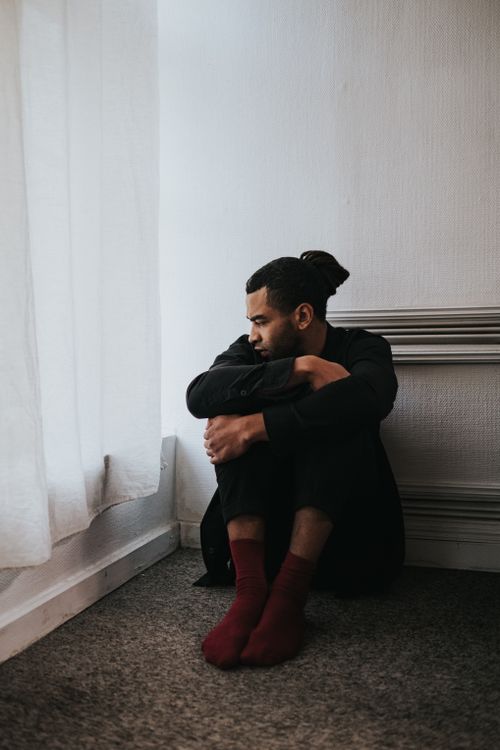 Free Thoughtful man sitting alone by a window, contemplating indoors. Stock Photo