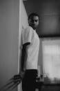 Grayscale Photo of a Man Leaning on a Wall