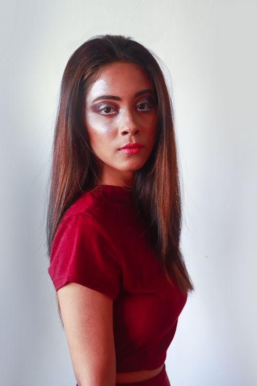 Free Charming young woman in red dress and bright makeup with long straight hair and brown eyes looking at camera while standing on white background Stock Photo