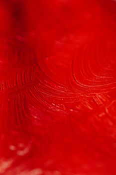 Close-up of a textured red surface with artistic brush strokes creating an abstract pattern.
