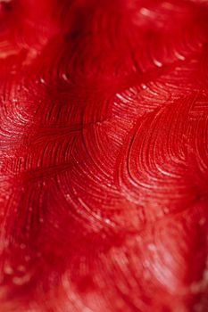 Close-up of a red abstract painting showing textured brush strokes.
