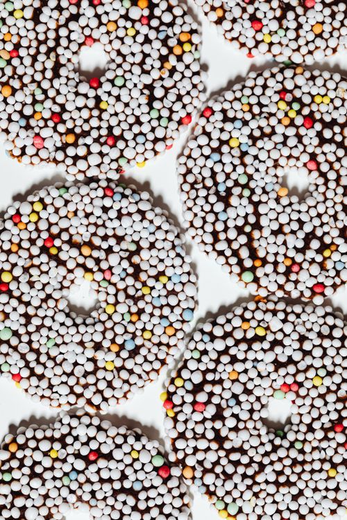 Free Top view of colorful chocolate-covered donuts with a sprinkle coating on a light backdrop. Stock Photo