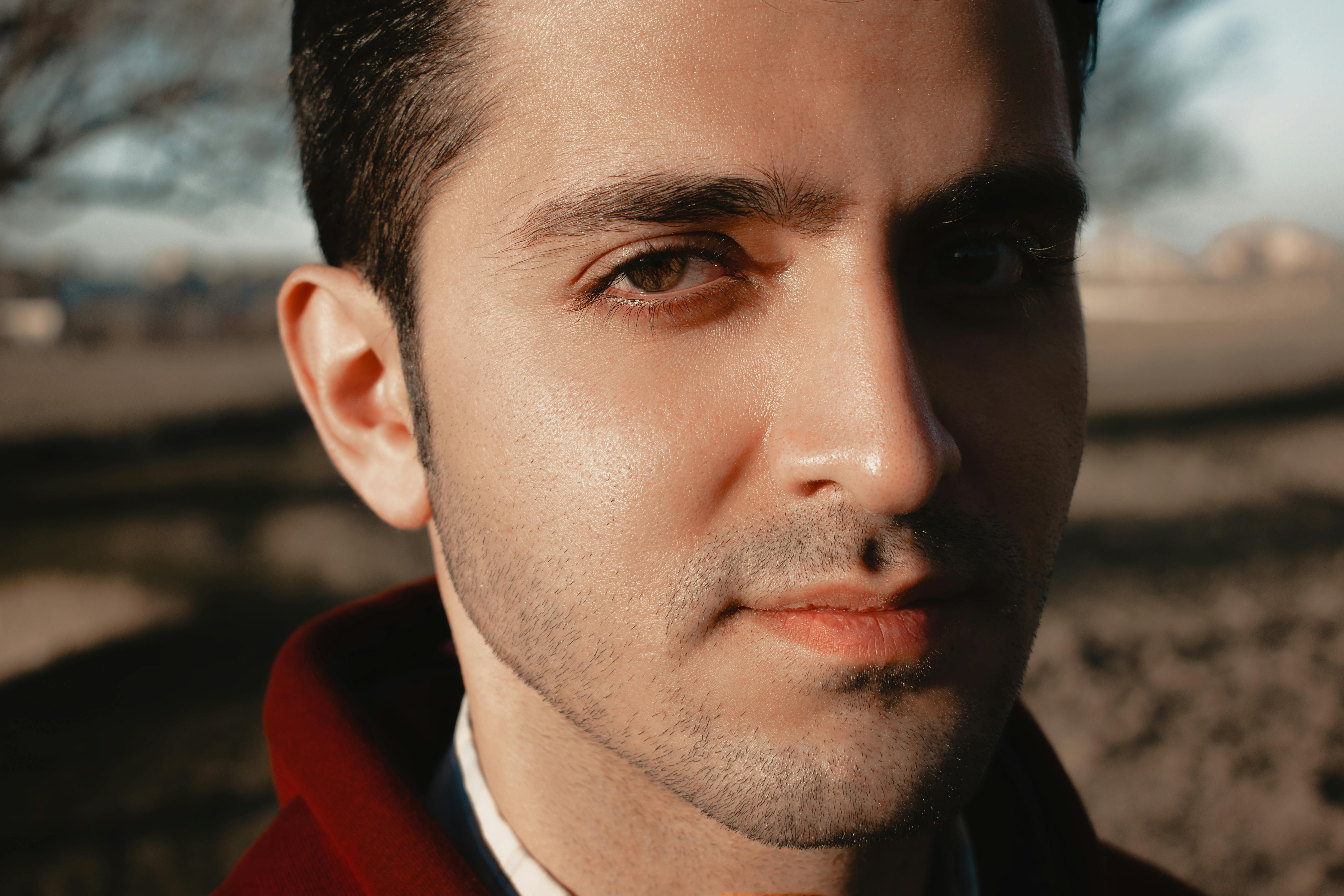 Close-up portrait of a man with a serene expression standing outdoors, captured in warm lighting.