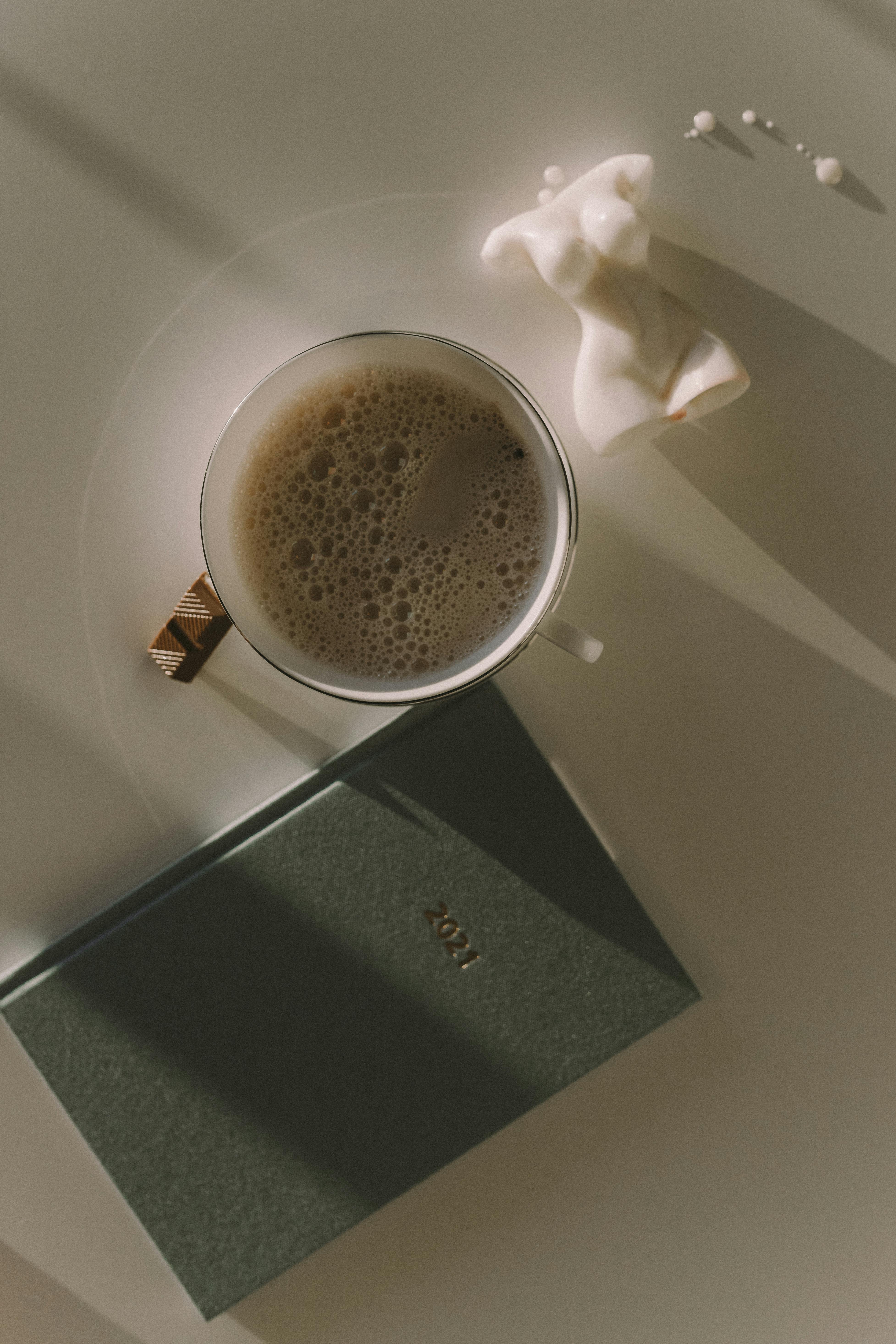 coffee in a white cup beside the notebook