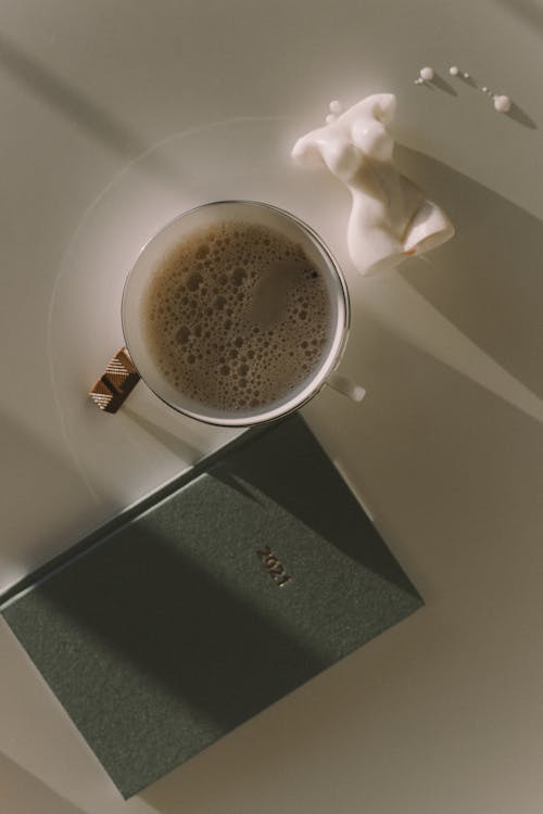 Free Coffee in a White Cup Beside the Notebook Stock Photo