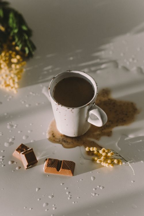 Free Coffee cup with chocolate bars and flowers, creating a cozy and inviting still life setting. Stock Photo