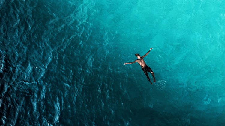 Man In Shorts Swimming In Blue Sea