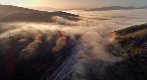 Fog over green hills and road in countryside