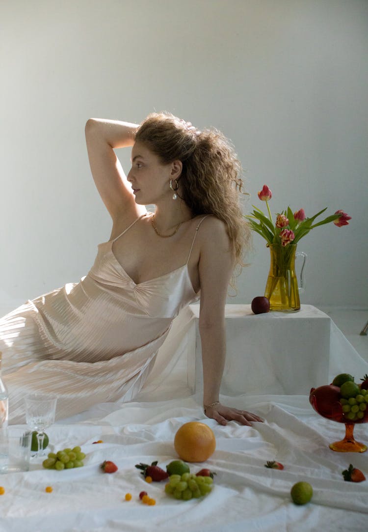 Woman In Satin Dress Among Tasty Fruits