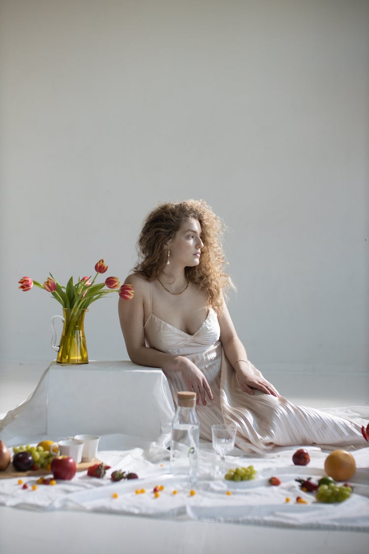 Young Gentle Woman Near Glass Vase With Red Tulips