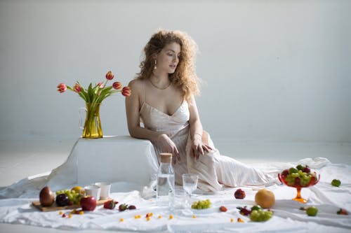 Elegant young woman near many sweet fruits and tulips