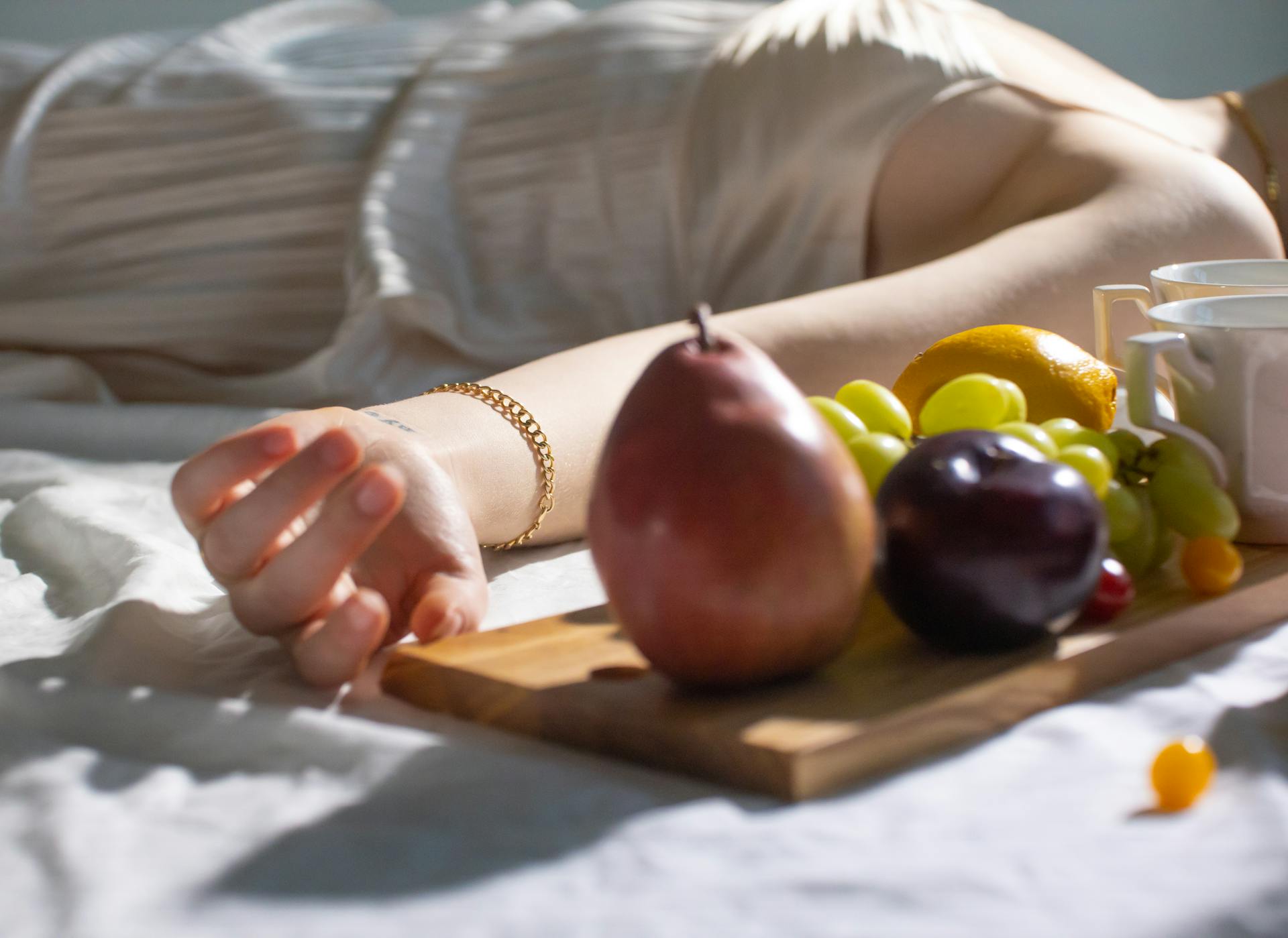 Fresh sweet fruits on timber board near woman