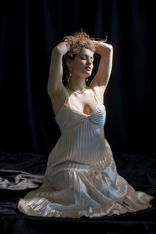 Graceful woman in dress in dark studio