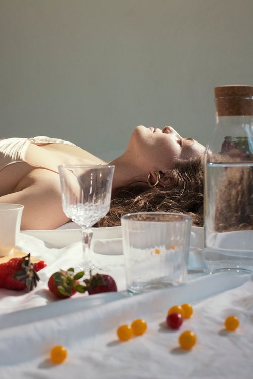 Free Side view of peaceful young feminine woman lying on blanket n floor with closed eyes near glassware and scattered berries Stock Photo