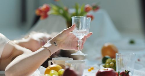 Free Charming young female with transparent wineglass resting on floor among flowers and fruits and cups Stock Photo