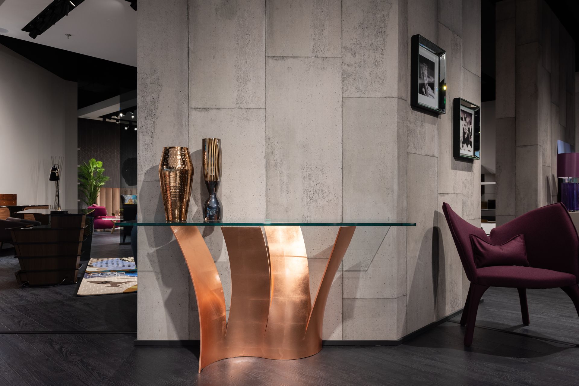 Modern glass table with decorative vases placed at wall decorated with pictures in spacious room with armchairs and contemporary furniture