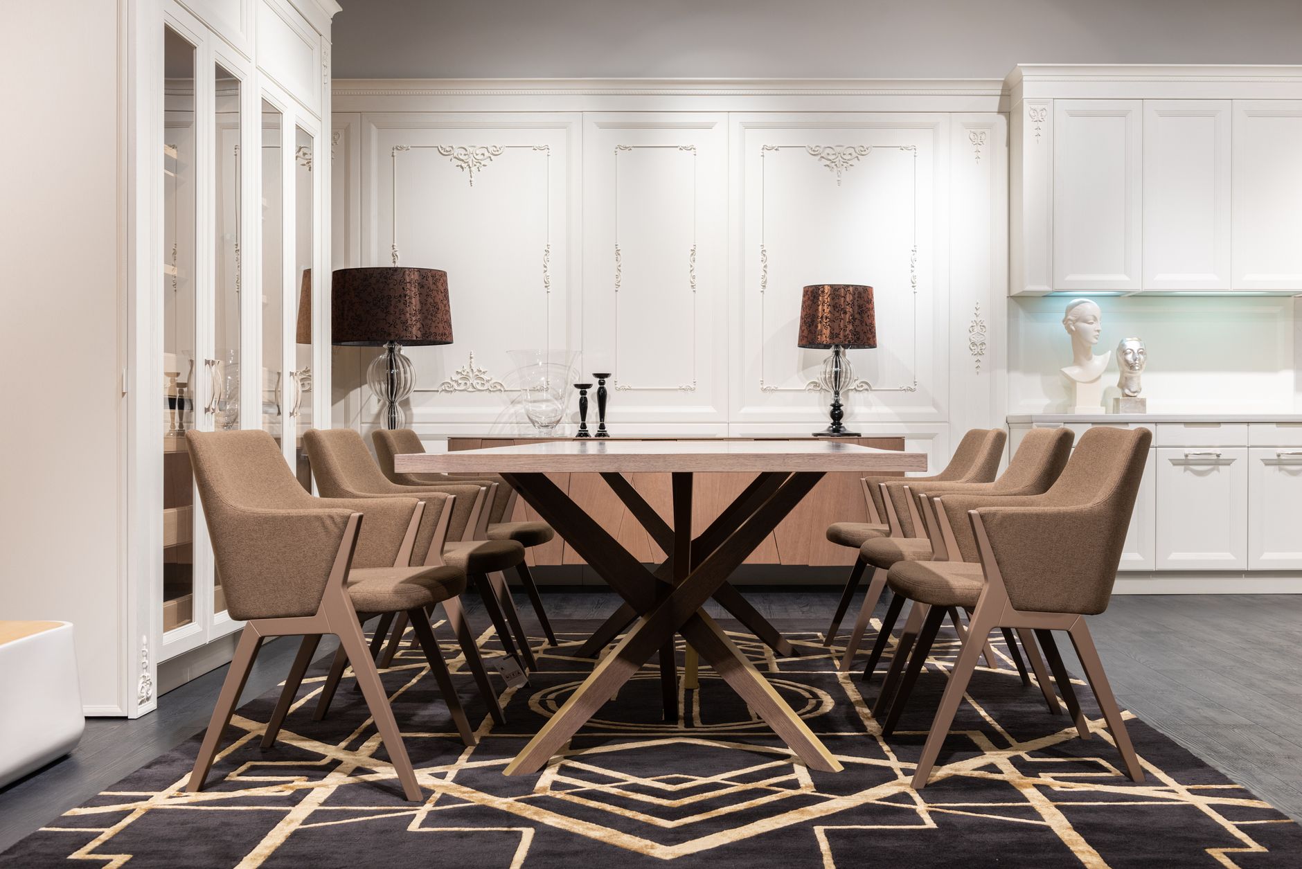 Contemporary table with set of chairs placed on rug in spacious kitchen with white cupboards and classic design at home