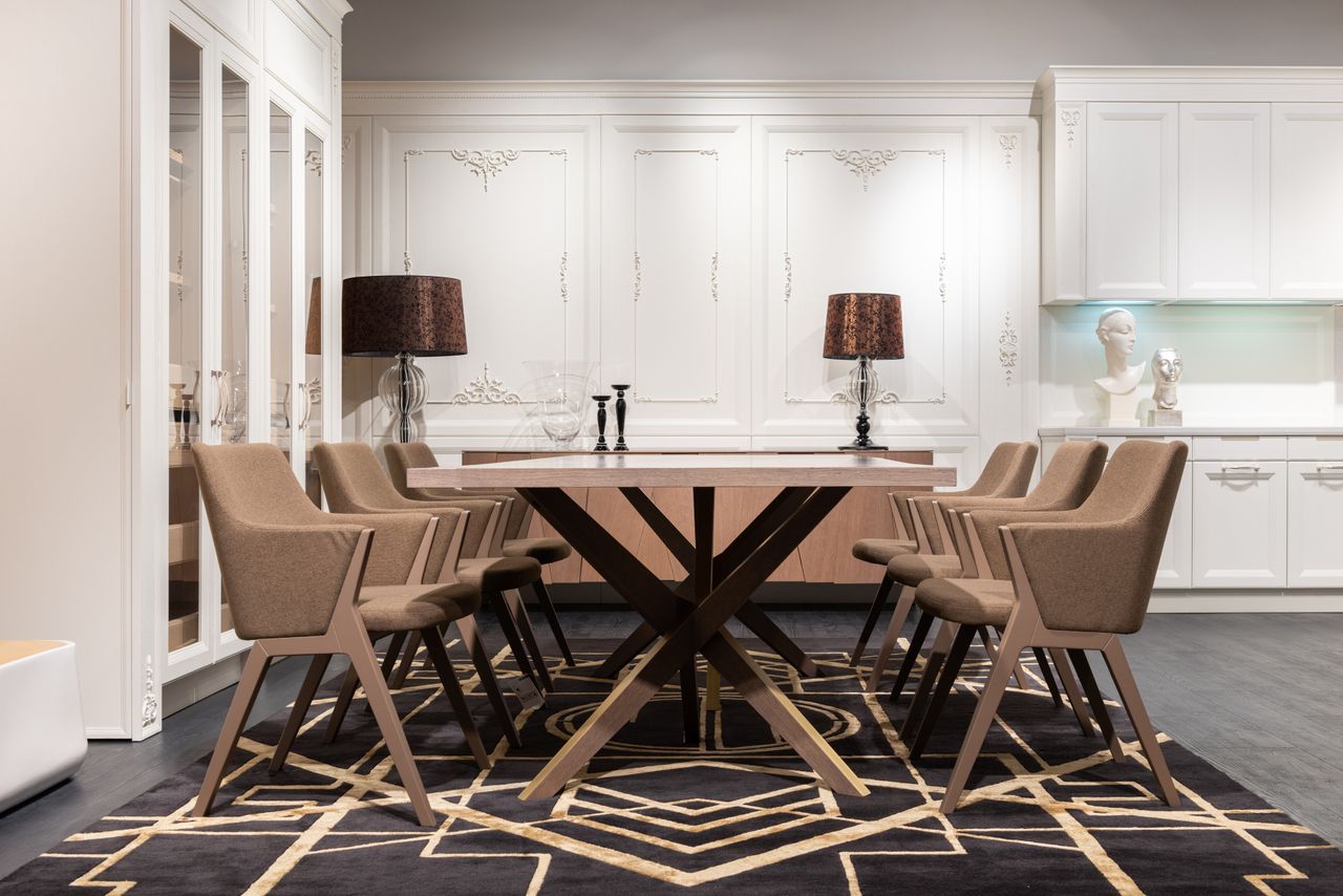 Taupe upholstered armchairs with arms on both sides of a long dining table