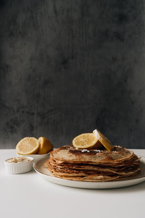 Free A delicious stack of freshly made crepes garnished with lemon slices and sugar. Stock Photo