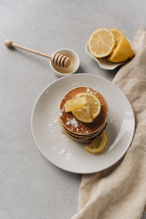 Free A stack of pancakes with lemon slices and honey, shot from above on a ceramic plate. Stock Photo