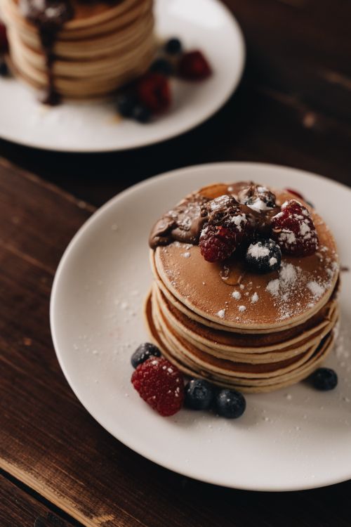 Free A stack of pancakes topped with mixed berries and chocolate, perfect breakfast treat. Stock Photo