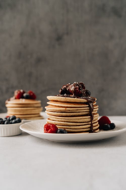 Free Mouthwatering pancakes with berries and chocolate syrup for a perfect breakfast. Stock Photo